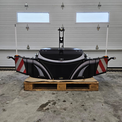 The TractorBumper Toolbox, a spacious black XL sealed toolbox with red-and-white striped panels, is placed on a wooden pallet in a garage with a white sectional door. Two white poles and integrated LED lighting enhance its functionality.